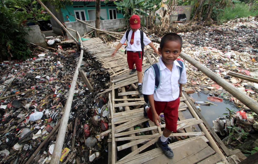 Dos niÃ±os cruzan un puente de bambÃº sobre un rÃ­o de basura en Bogor, Indonesia. 