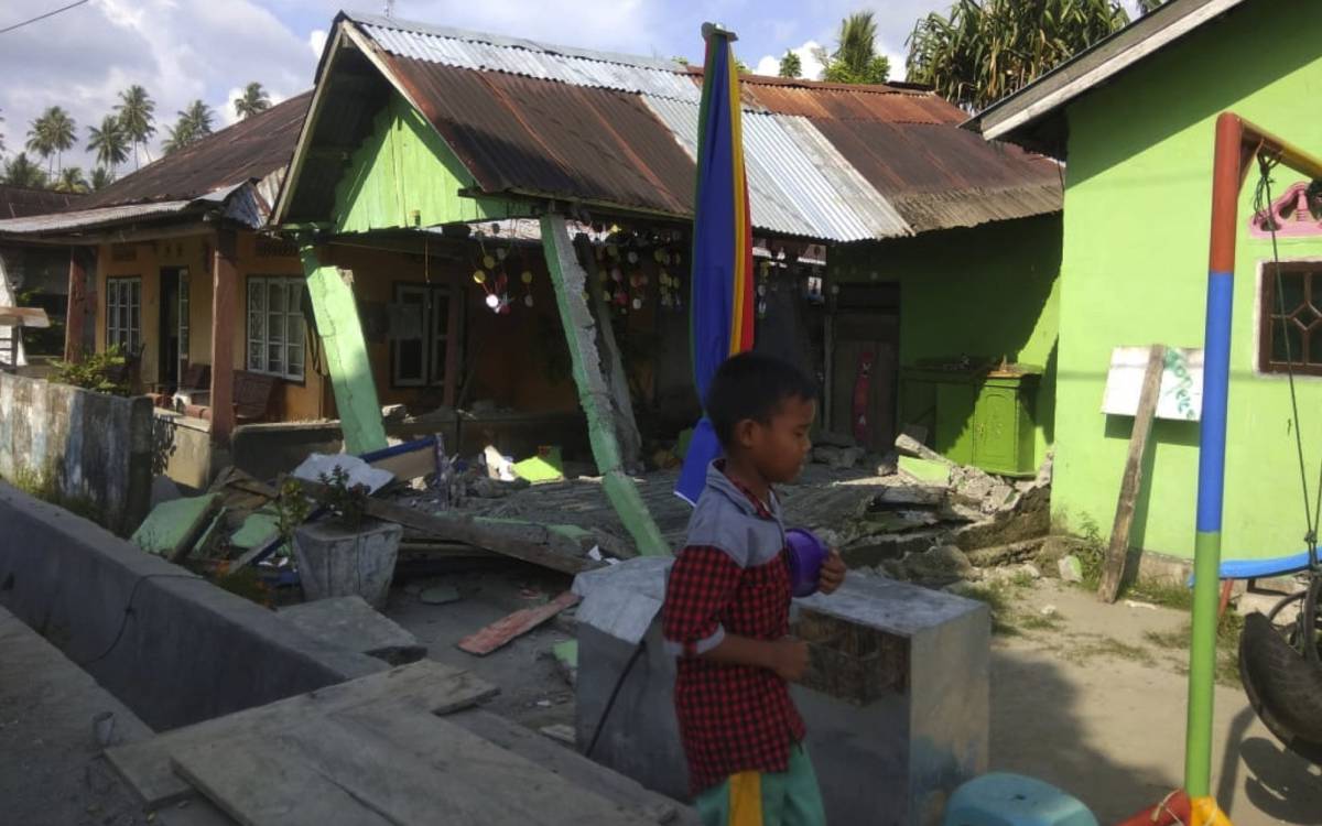 Un menor ante una casa destruida, en Donggala.