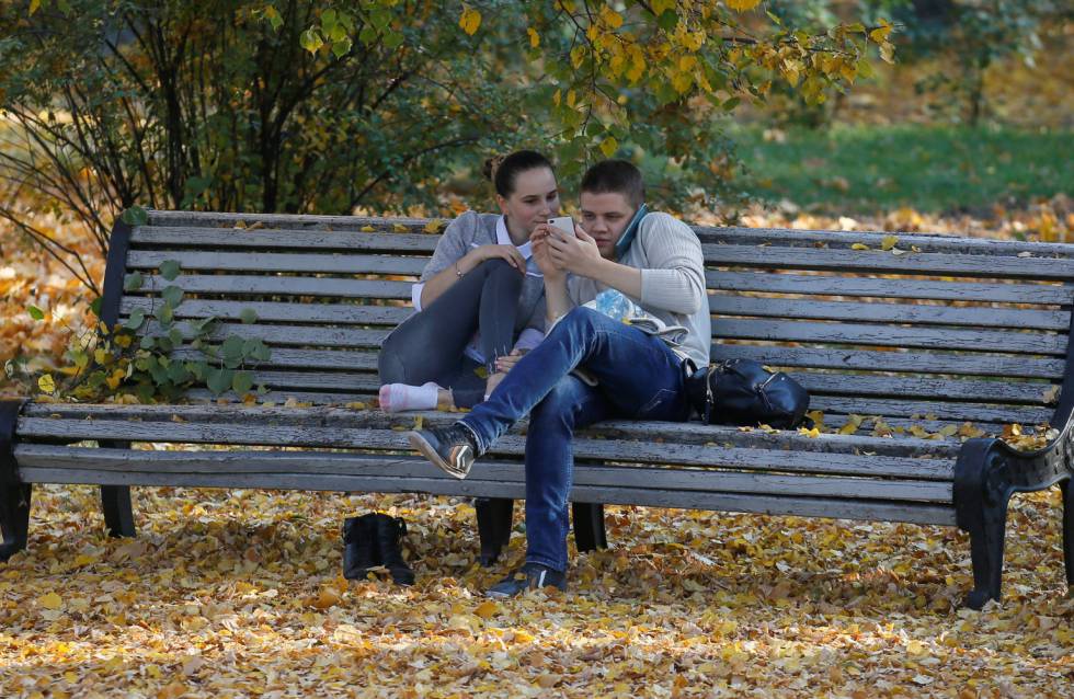 Una pareja de jóvenes observa un móvil en un parque en Kiev.