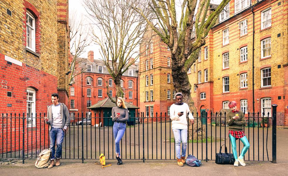 Jóvenes de distintas razas miran sus smartphones en Londres. 