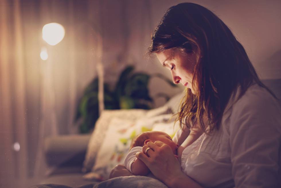 Una madre amamanta a su bebÃ© por la noche. 