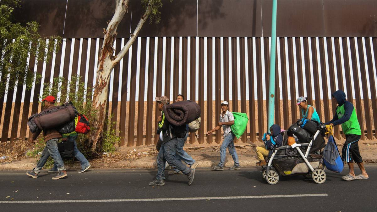Inmigrantes caminan este martes por la valla de Mexicali (México).