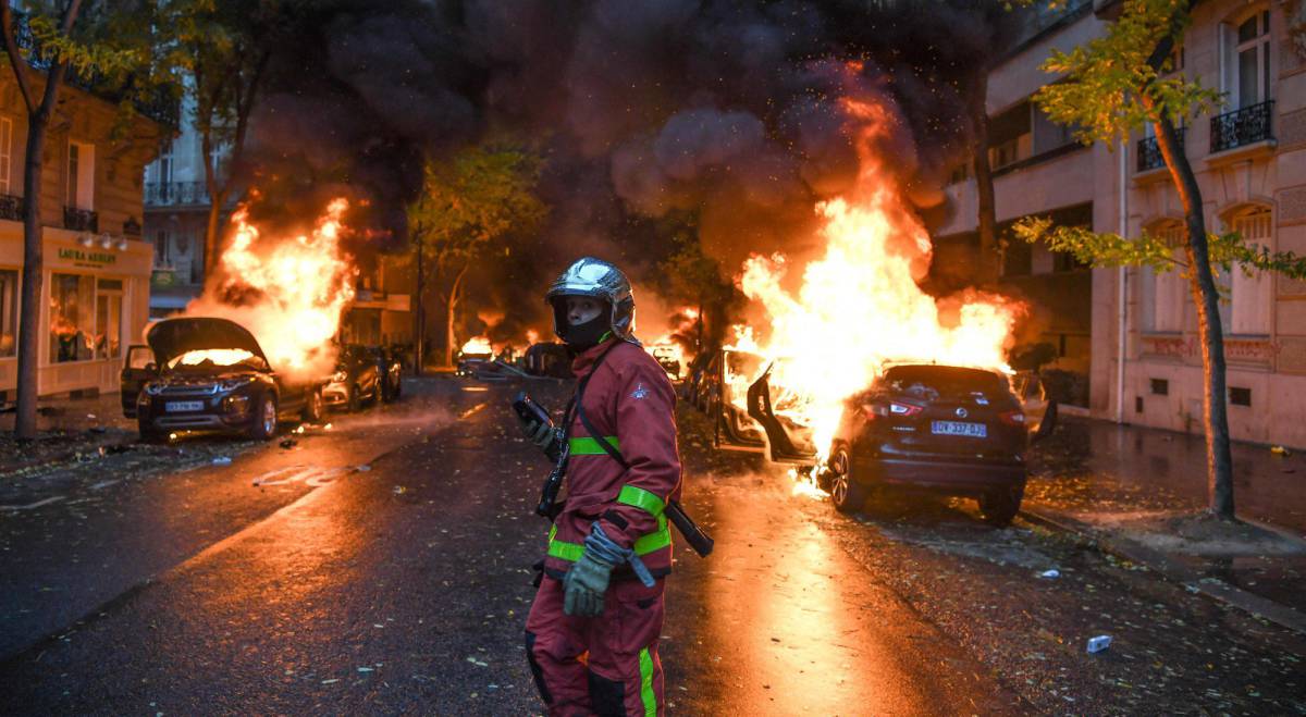 Un bombero junto a varios vehÃ­culos ardiendo en el centro de ParÃ­s.
