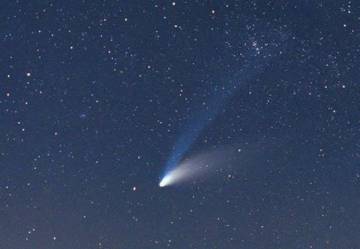 El cometa Hale-Bopp tiene una cola de iones azul y una cola de polvo curva. 