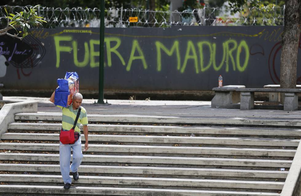 Un hombre pasa junto a una pintada contra Nicolás Maduro en Caracas.