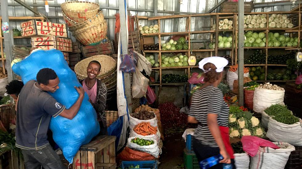 Una mujer con gorro blanco y delantal en el mercado de vegetales de Addis Abeba.