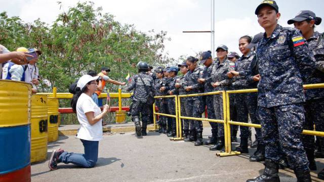 Una seguidora de Guaidó se arrodilla ante la Guardia Nacional.