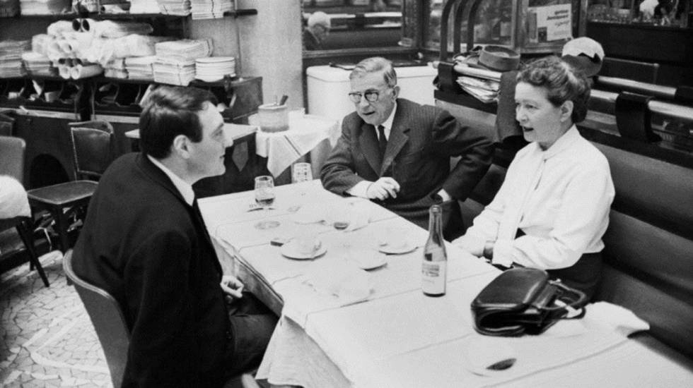 Simone de Beauvoir junto a Jean-Paul Sartre y Claude Lanzmann cenando en un restaurante de ParÃ­s.