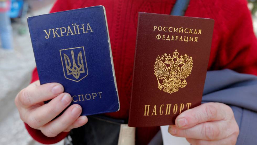 Una mujer muestra un pasaporte ucraniano y uno ruso.