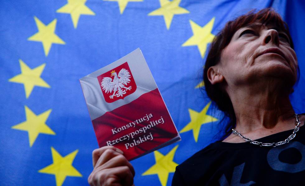 Una mujer con la ConstituciÃ³n de Polonia, bajo una bandera de la UE. 