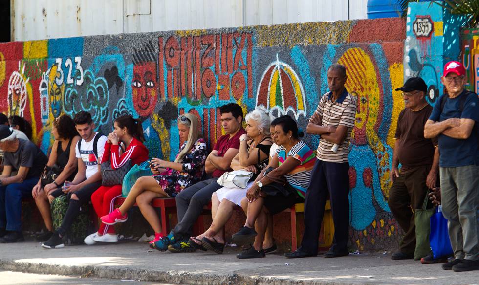 Un grupo de personas esperando en una parada de ómnibus.