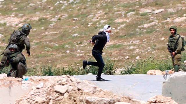 Un joven palestino huye de tropas israelíes el jueves en Cisjordania.