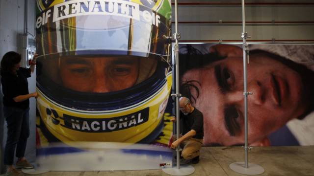 Operarios cuelgan fotos de Senna en una exposición.