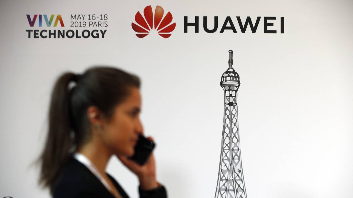Una mujer delante del logo de Huawei.