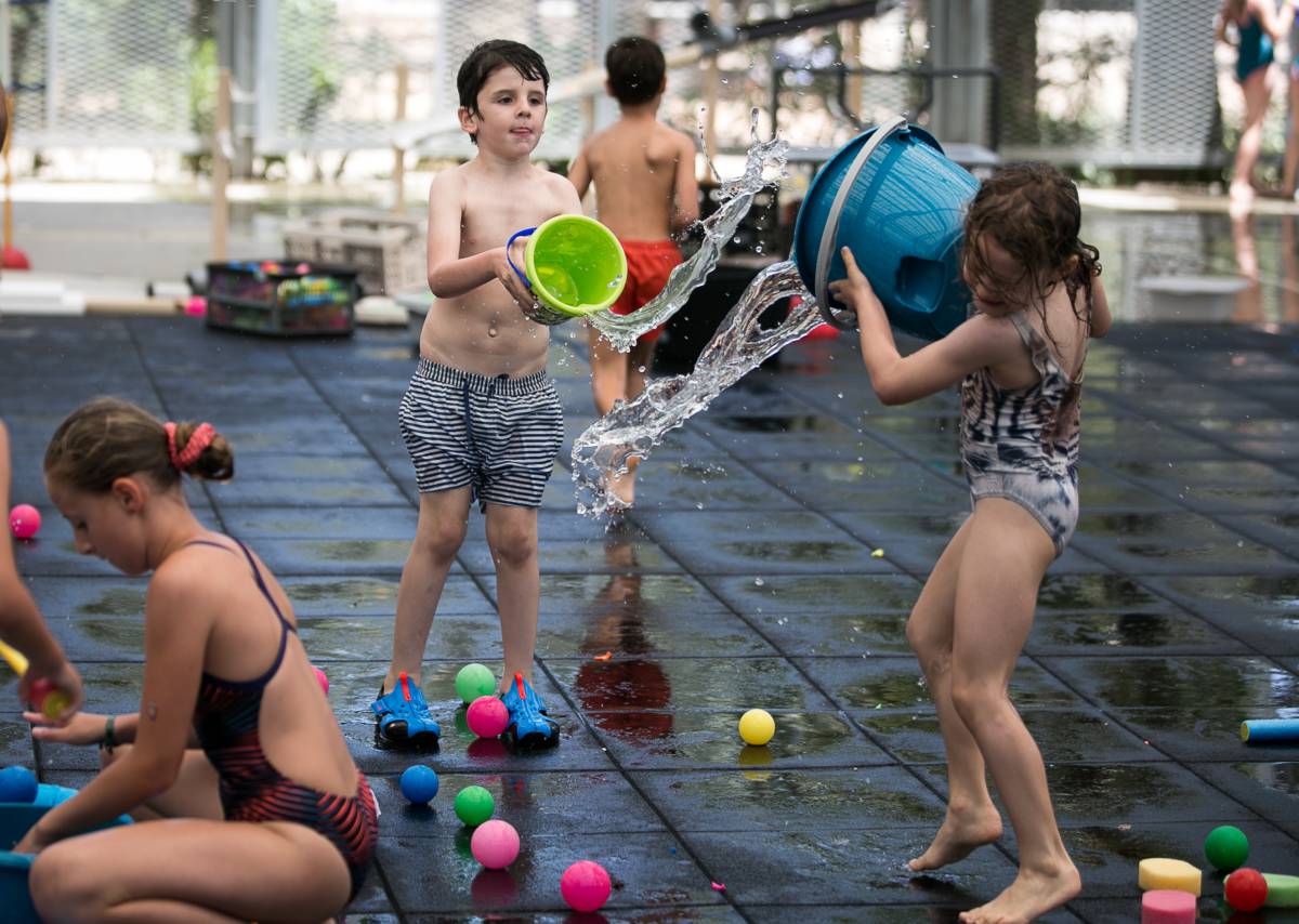 Varios niños juegan con agua en el nuevo espacio del parque Joan Miró, en Barcelona, este martes.