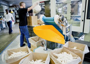 Trabajador saca de un contenedor cubiertos hechos con plástico de un solo uso. 