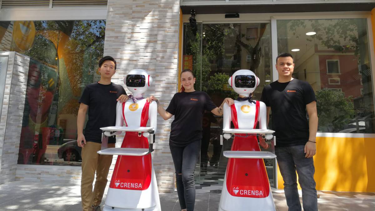 Tres empleados y dos robots del restaurante Crensa.