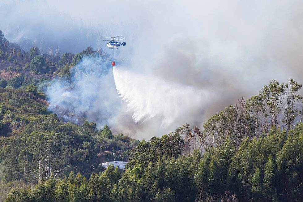 A helicopter drops water onto the forest fire in Guía, Gran Canaria.