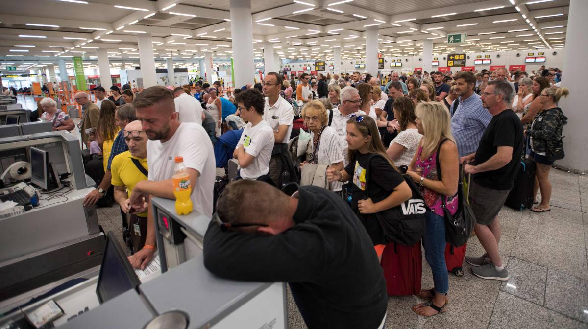 Pasajeros hacen cola frente a un mostrador en el aeropuerto de Palma de Mallorca.