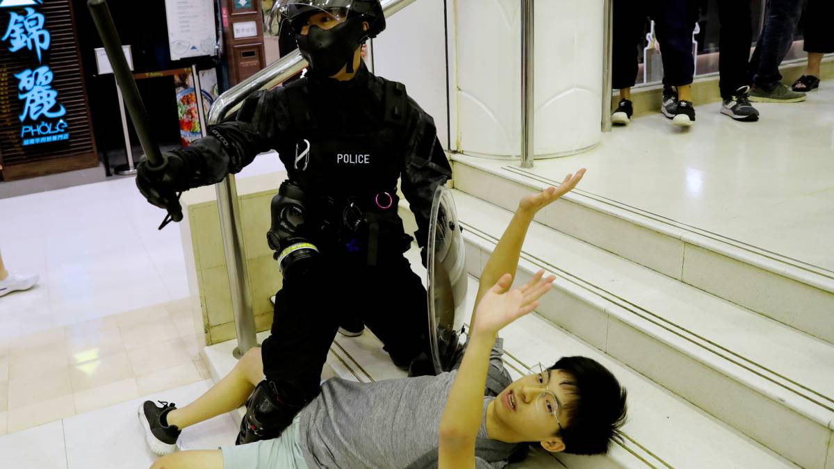 Un policía detiene a un joven en el centro comercial de Tai Po.