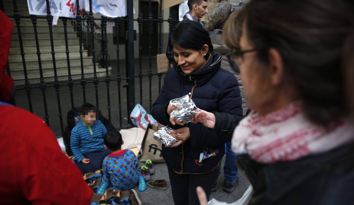 Familias reparten la merienda a demandantes de asilo, este martes en Madrid.