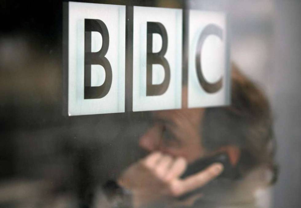Un hombre habla por teléfono tras un cristal con el logo de la BBC.