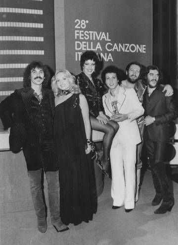 La presentadora italiana Maria Giovanna Elmi, sentada en el centro, sonríe junto a los miembros de Matia Bazar, ganadores del Festival de San Remo de 1978.