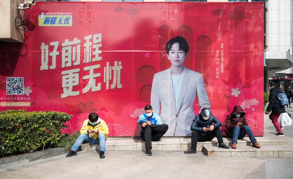 Cuatro repartidores con mascarillas junto a una boca de metro en Shangai, el 27 de febrero pasado.
