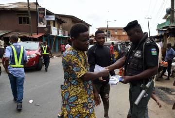 Un policía distribuye información en una calle de Lagos, Nigeria.