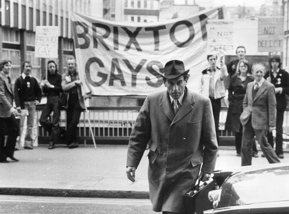 Jeremy Thorpe llega al juzgado donde se decidía si era culpable de asesinato en 1979. Detrás de él, activistas gais sujetan una pancarta.