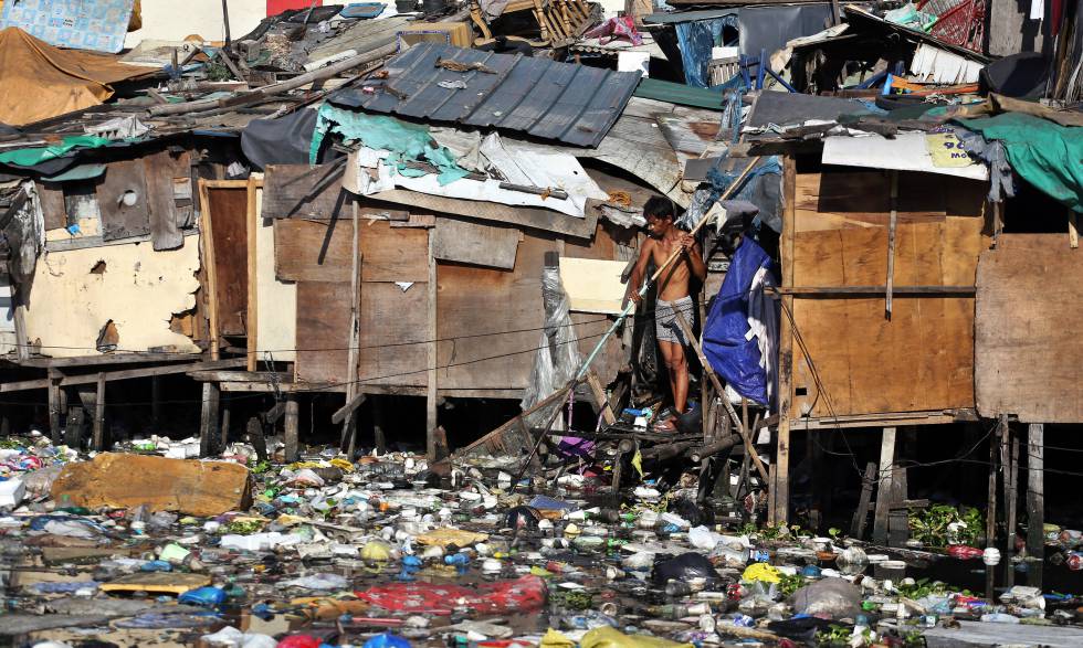Un hombre escarba entre la basura que cubre el agua de un río al fondo del slum donde tiene su casa, en Pritil, Estero de Vitas, en el distrito de Tondo, en Manila.