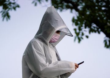 Un hombre con un equipo de protección contra la Covid-19 usa un teléfono móvil.