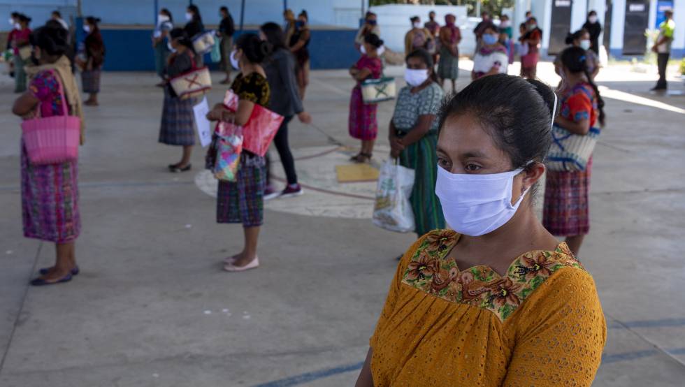 Varias mujeres y niñas esperan su turno para recoger suministros en un colegio en Guatemala.
