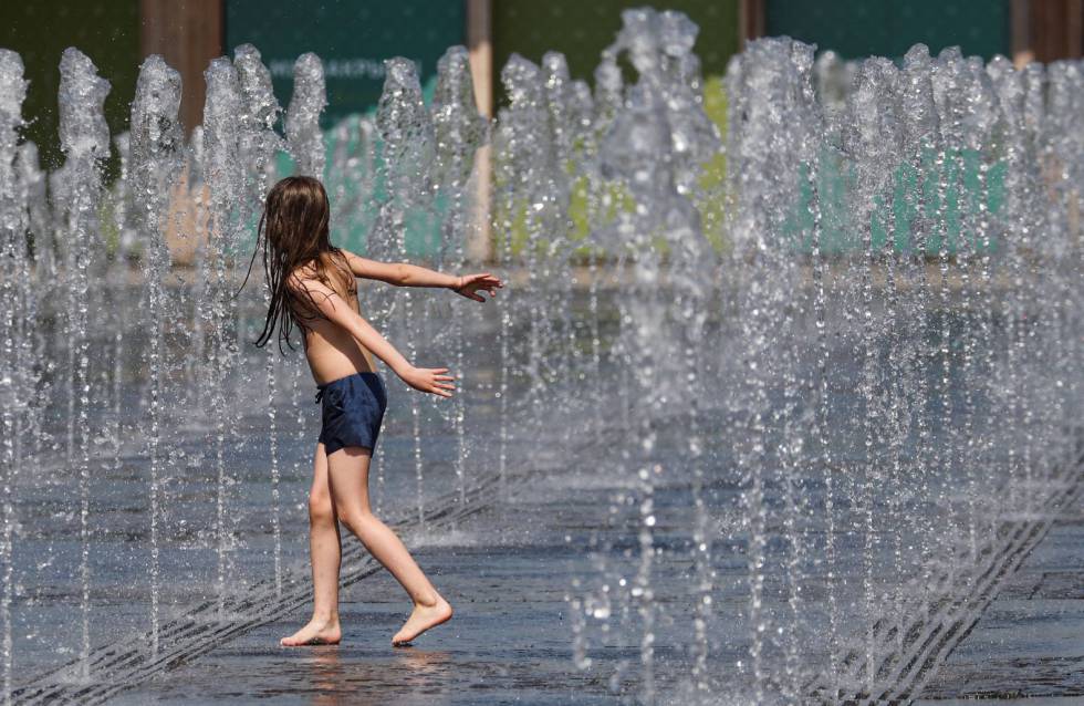Un niño juega con chorros de agua en un día de calor en Moscú, Rusia. 