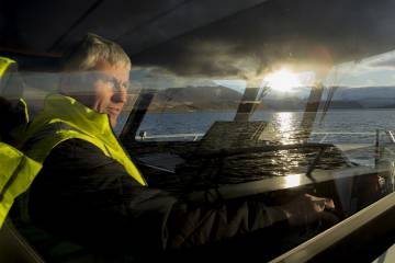 An operator drives the boat to the salmon-growing rings, located in the middle of the sea on the island of Skjervøya.