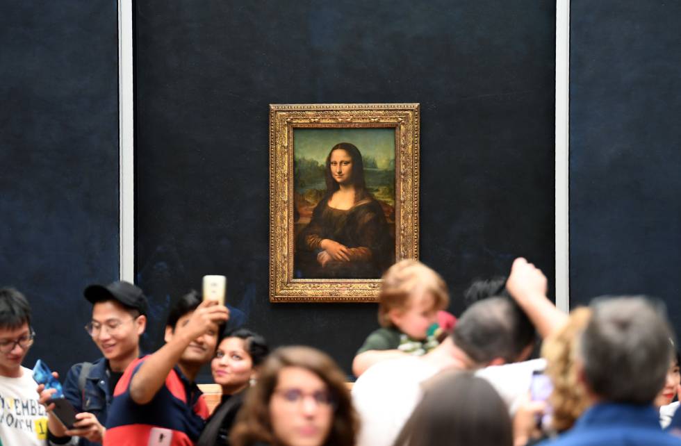 Un grupo de turistas fotografía con sus móviles a 'La Mona Lisa', expuesta en el Museo Louvre de París.