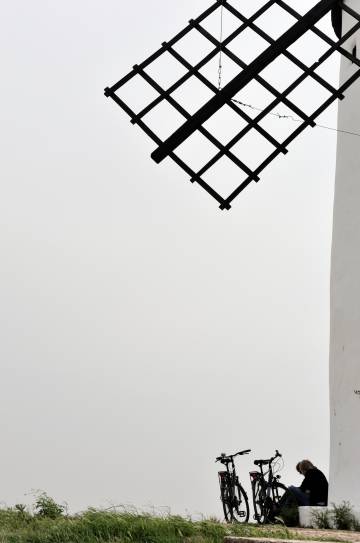 Dos ciclistas descansan bajo las aspas de los molinos de viento del Cerro de San Antón, en Alcázar de San Juan (Ciudad Real).