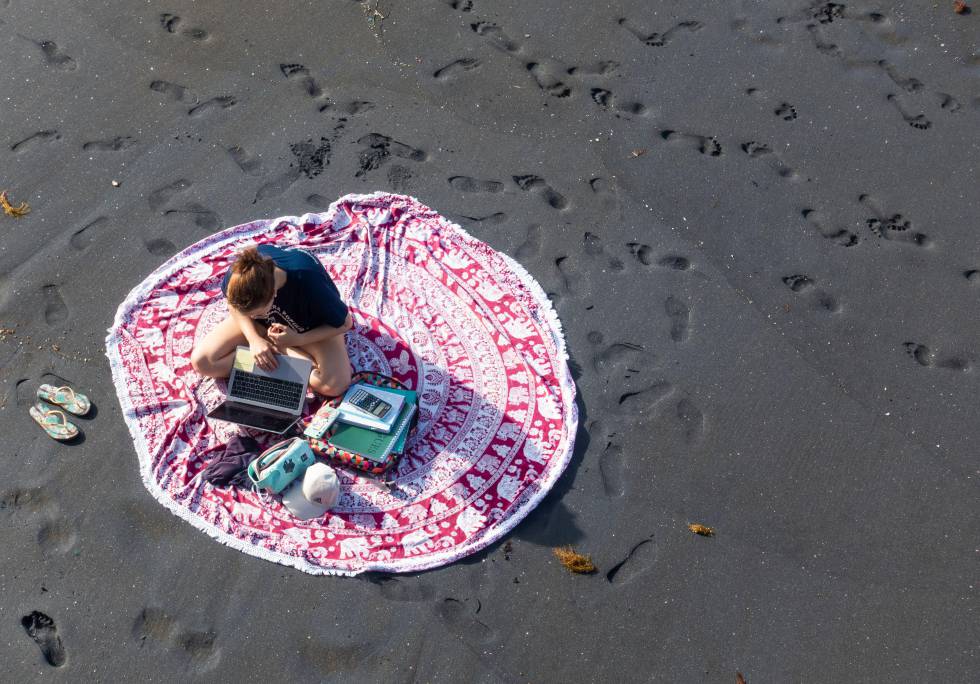 Una mujer trabaja sobre la arena de una playa de Las Palmas, en la isla de Gran Canaria.