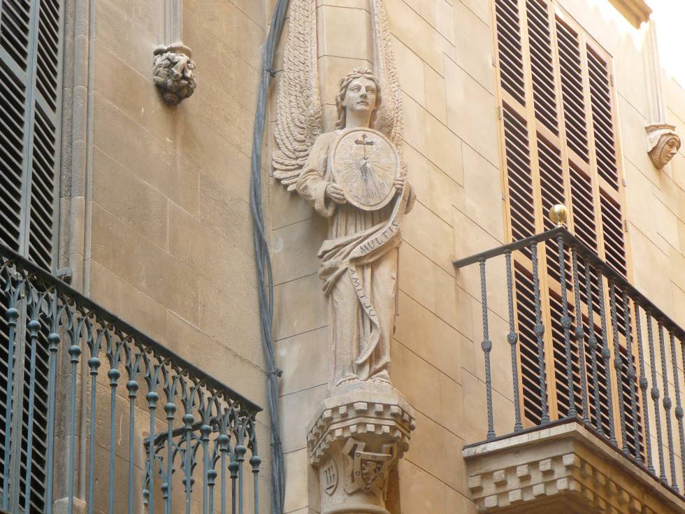 Elliptical clock held by an angel on Calle de Portella in Palma.
