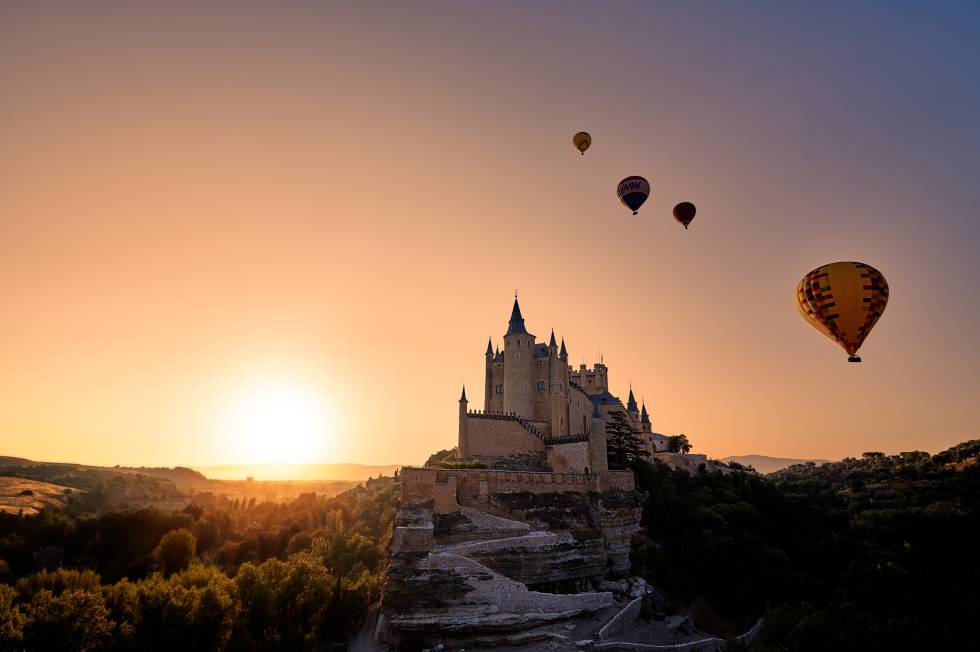 Hot air balloons taking off at dawn next to the Alcazar of Segovia.