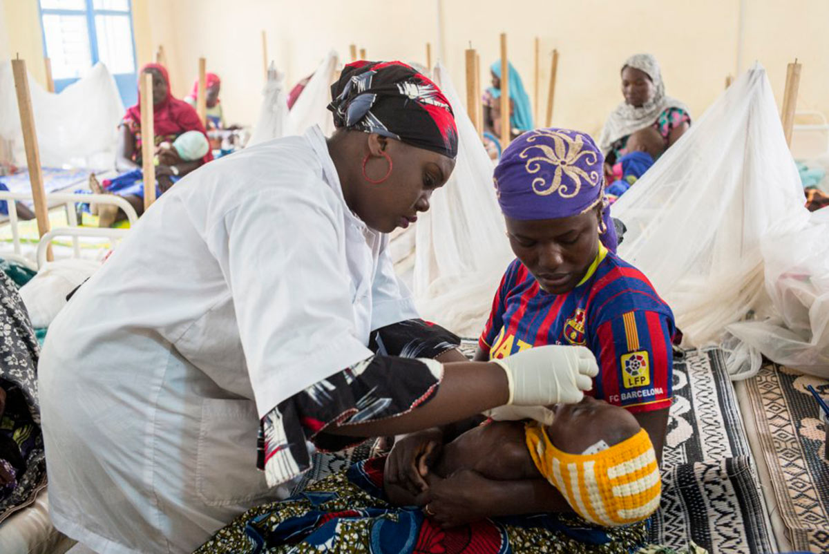 Barkissa Seydou, enfermera de 22 años, revisa el estado de Zeynabou, de 24 meses, en brazos de su madre, la señora Issoufou