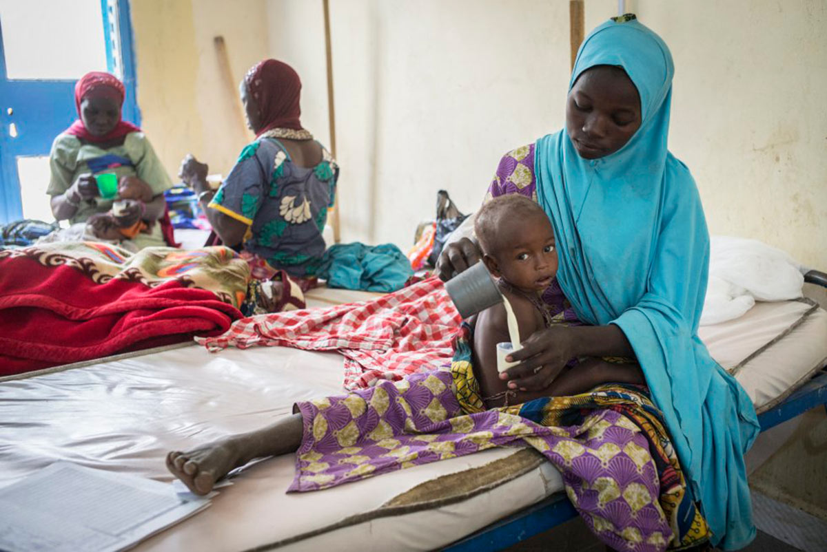 Hamissou prepara un vaso de leche a su hijo de 15 meses Amrazak en el CRENI de Mayahí