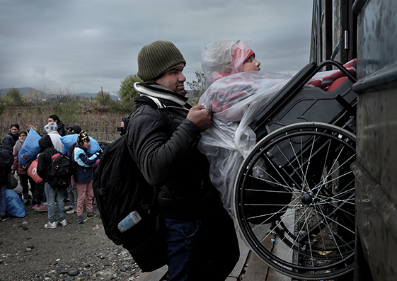 Abdullah Hussein, un refugiado de 12 años de Irak, es levantado a duras penas en su silla de ruedas para subirse a un tren en la frontera con Grecia, en noviembre de 2015.