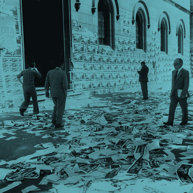 Entrada a un edificio público con el suelo y paredes llenas de papeles de los candidatos