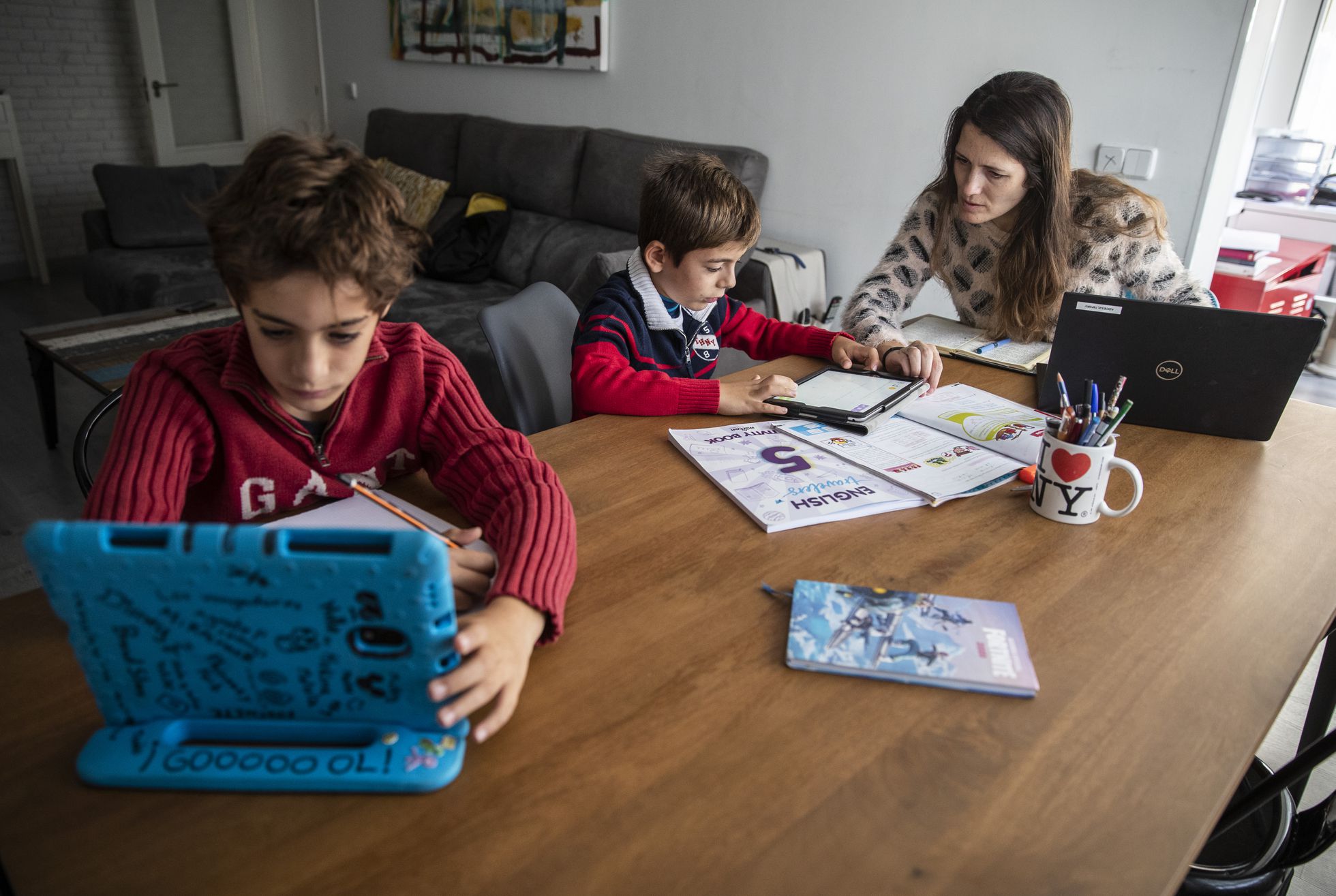 Mujer teletrabajando en casa mientras ayuda a sus hijos con los deberes, en su domicilio de Madrid.