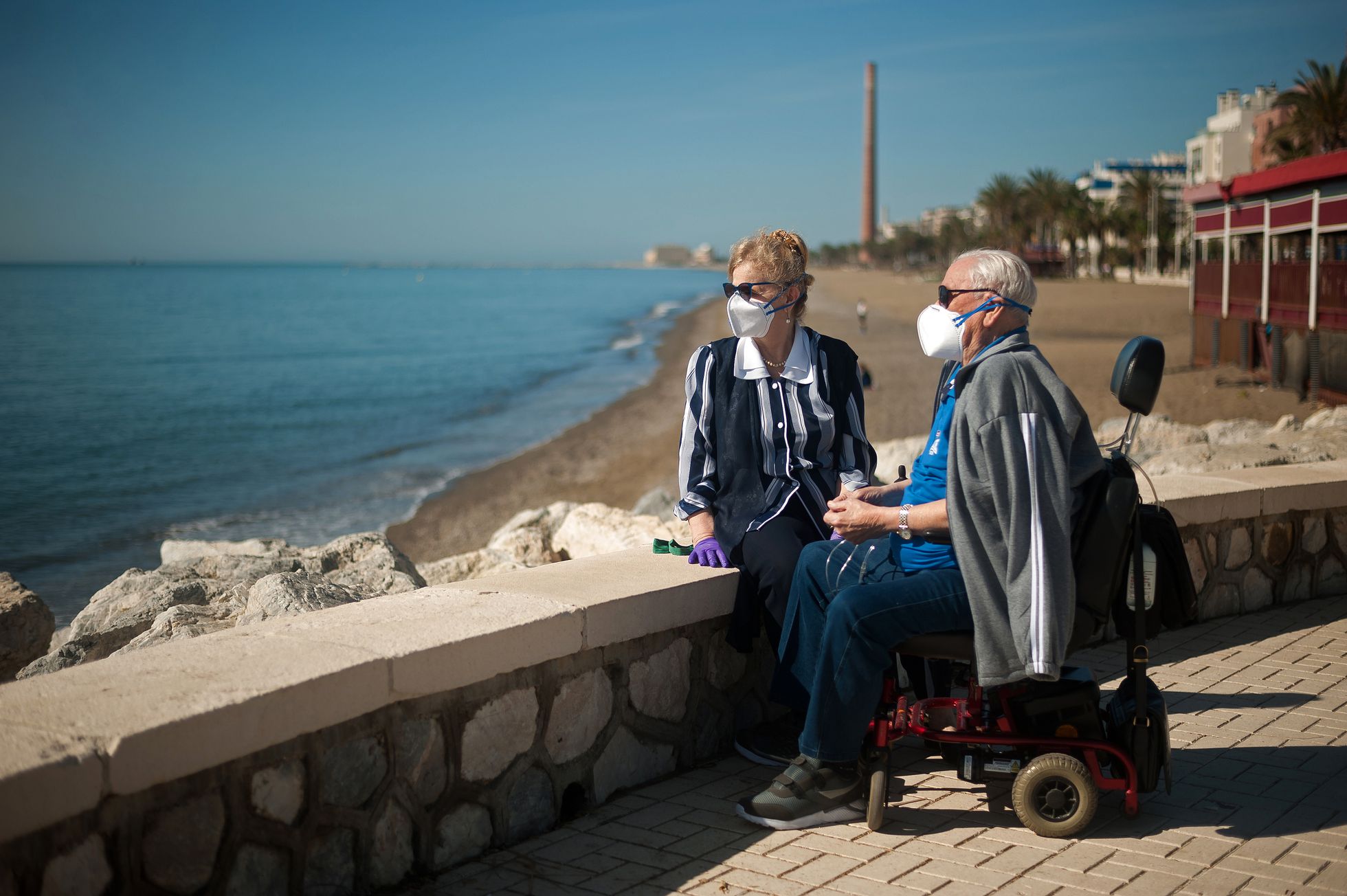 Una pareja de pensionistas descansa en el paseo marítimo de una playa malagueña.