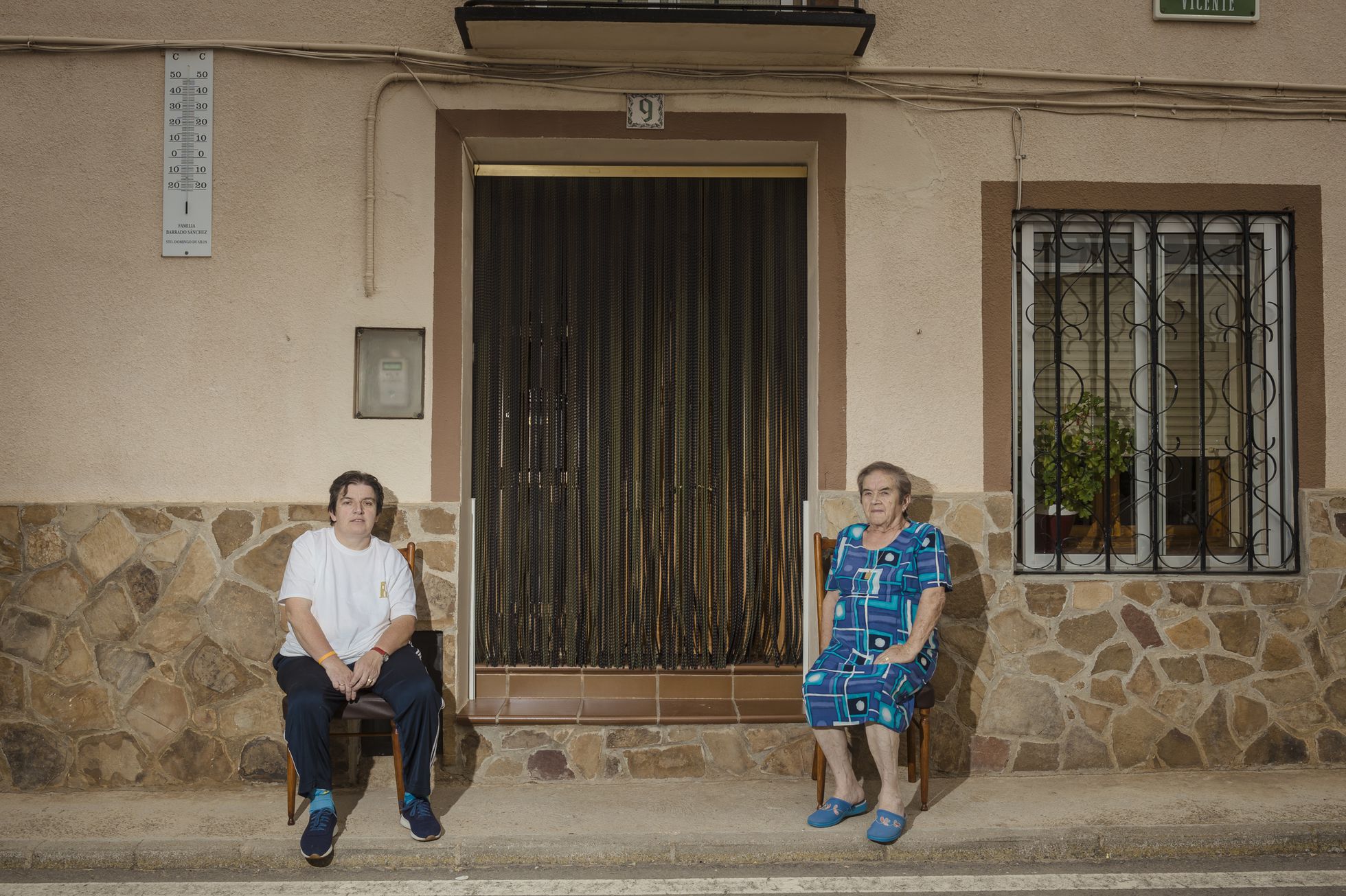 Maruja Sánchez, de 83 años, con su hija María José Barrado, de 51, sentadas a la fresca frente al portal de su casa en Bello (Teruel).