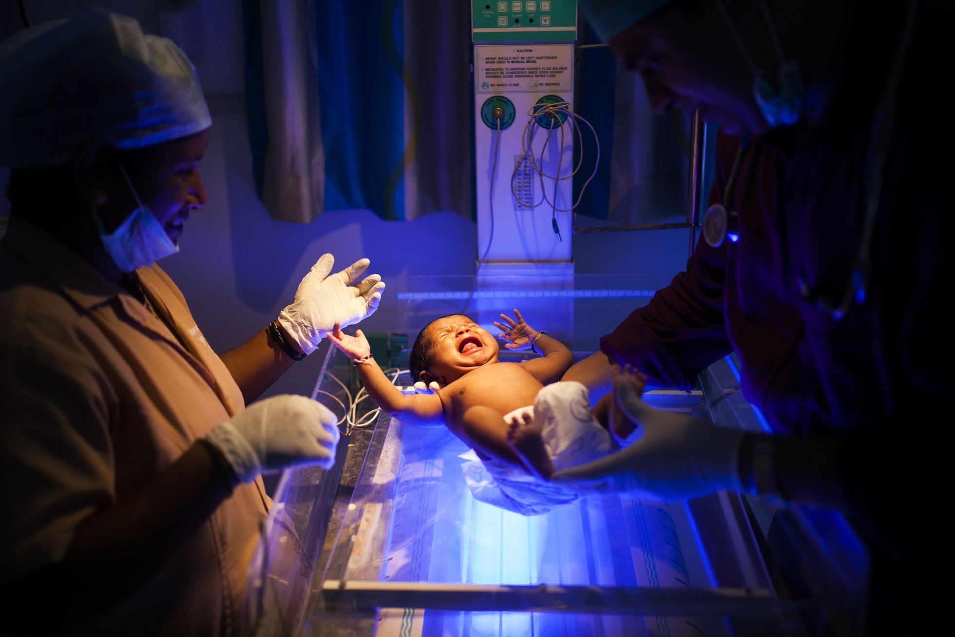 El doctor Rakh y una enfermera examinan a una niña recién nacida que llora en la incubadora.