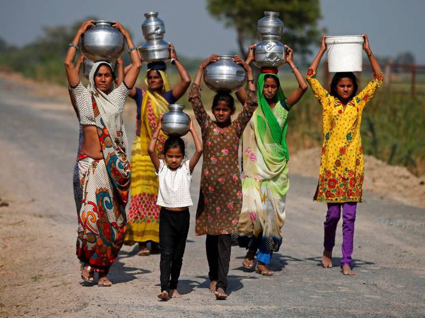 Mujeres y niñas indias transportan agua en las afueras de Ahmedabad el pasado sábado.