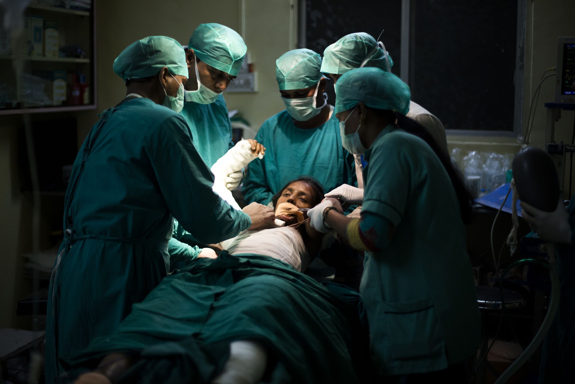 En la sala de operaciones, un cirujano y los médicos del hospital operan a Jaya para liberar su brazo.